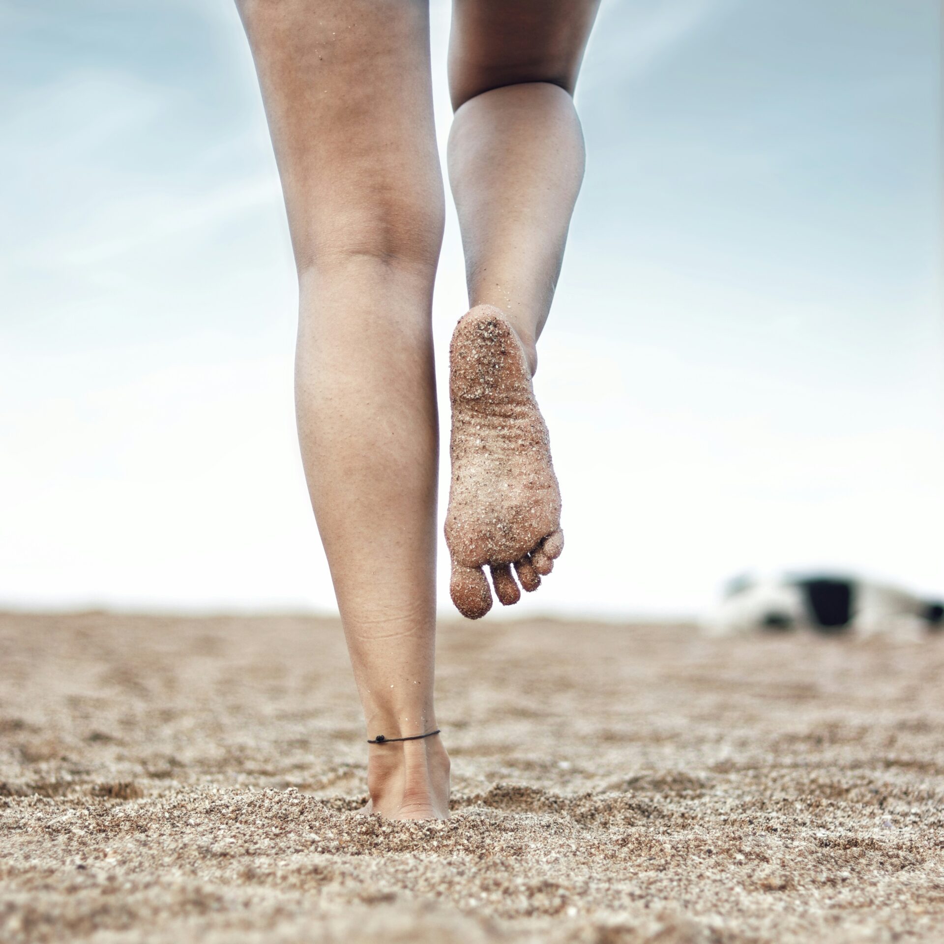 Person walking on sand. Bottom of foot and heel visible.
